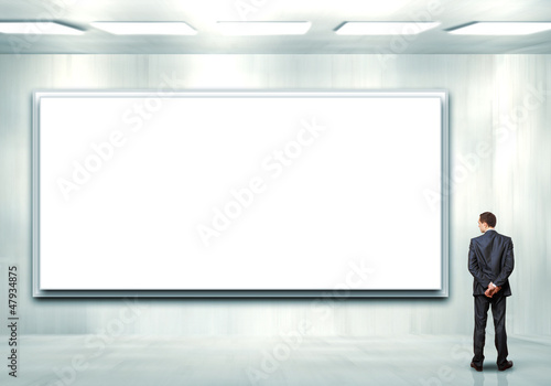 Business person standing near a blank billboard © Sergey Nivens