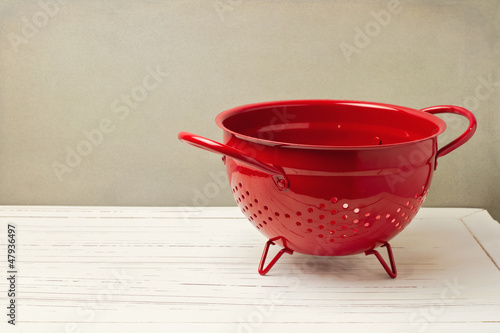 Red empty colander on white wooden table