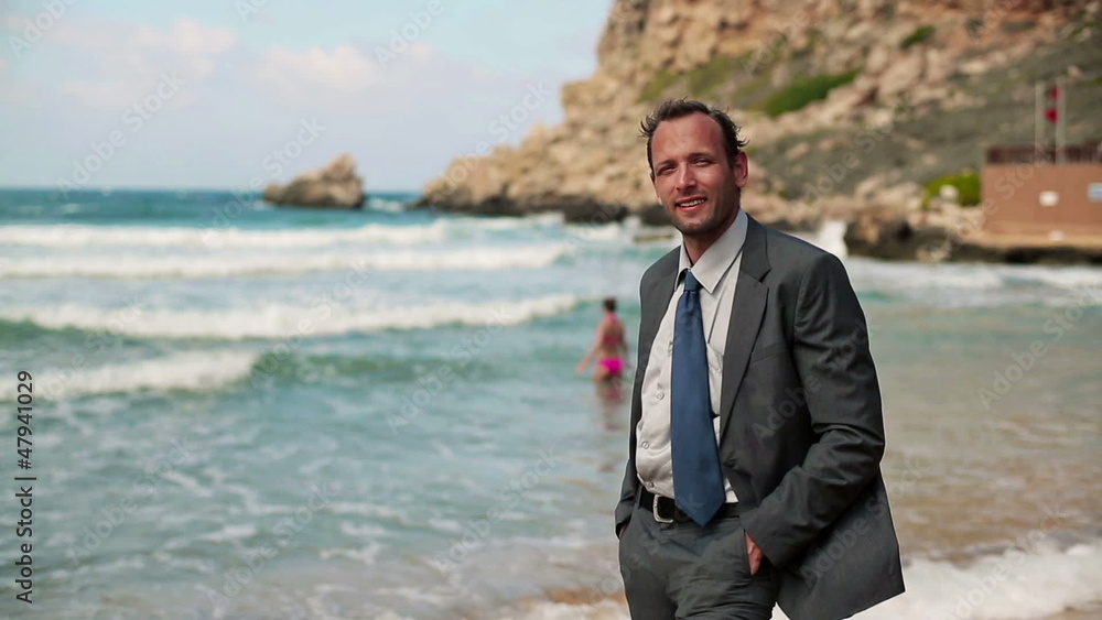 Young happy businessman standing on the beach Young happy businessman standing on the beach