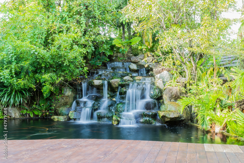 Artificial waterfall with wooden deck in garden Artificial waterfall with wooden deck in garden