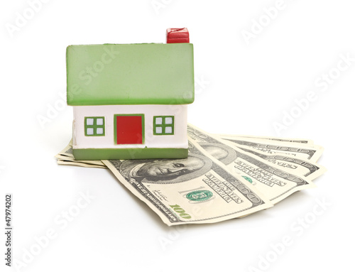 Model of a house lying on some banknotes isolated on white