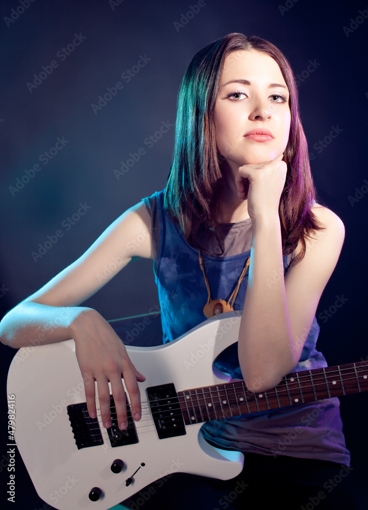 Young beautiful woman is sitting on stage with a guitar . Fog on