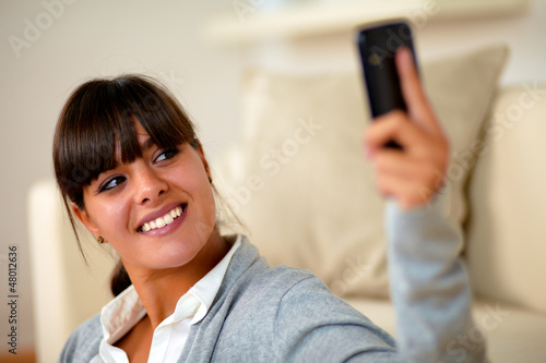 Smiling young woman taking a photo with cellphone