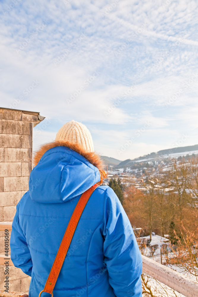 Woman from back looking over village in snow valley. Woman from back looking over village in snow valley.