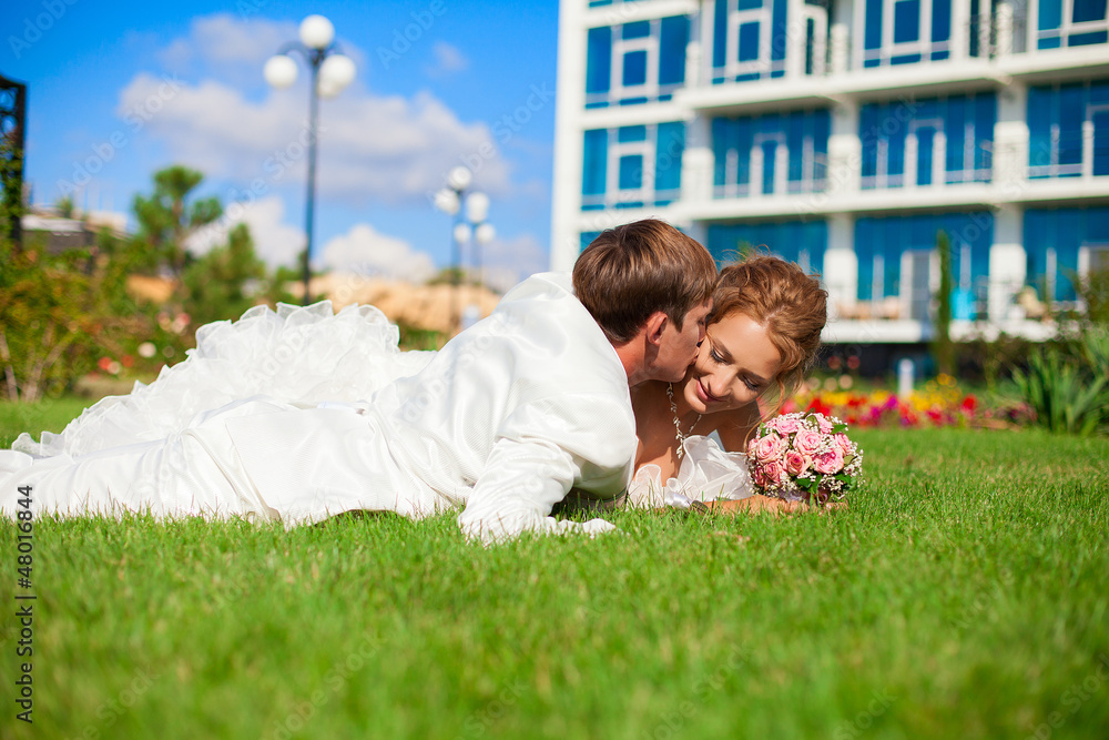 Naklejka premium couple with bouquet posing in park lying on the green grass