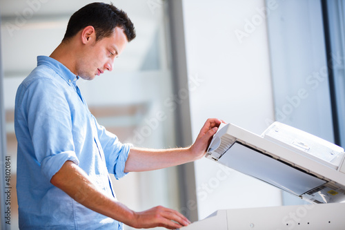 Bild auf Leinwand Handsome  young man using a copy machine