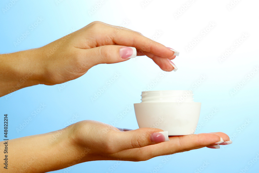 Beautiful woman hands with cream, on blue background Beautiful woman hands with cream, on blue background