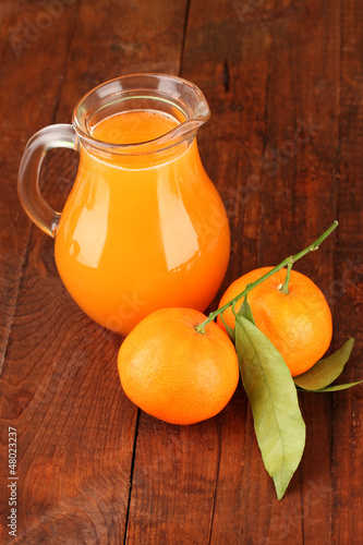 Full jug of tangerine juice, on wooden background