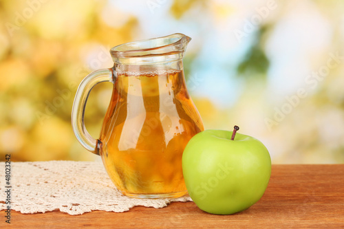 Full jug of apple juice and apple