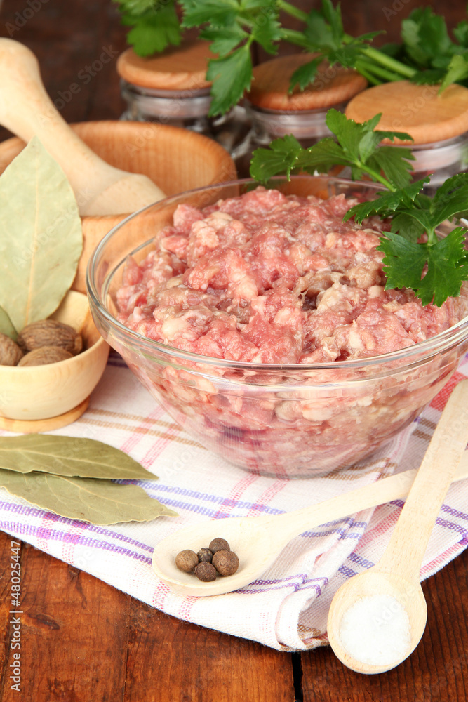 Bowl of raw ground meat with spices on wooden table Bowl of raw ground meat with spices on wooden table