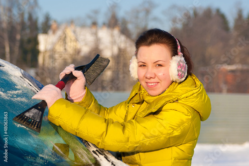 Girl cleaning car from snow
