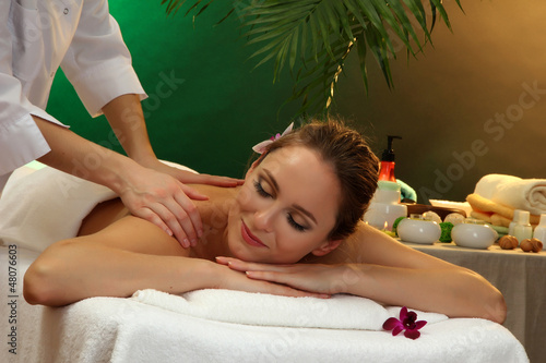 beautiful woman in spa salon with stones getting massage 