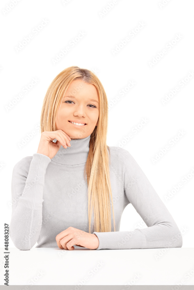 A smiling blond female posing on a table A smiling blond female posing on a table