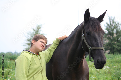Smiling teenager boy with horses at the field