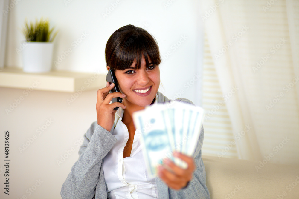 Smiling woman speaking on cellphone with money Smiling woman speaking on cellphone with money