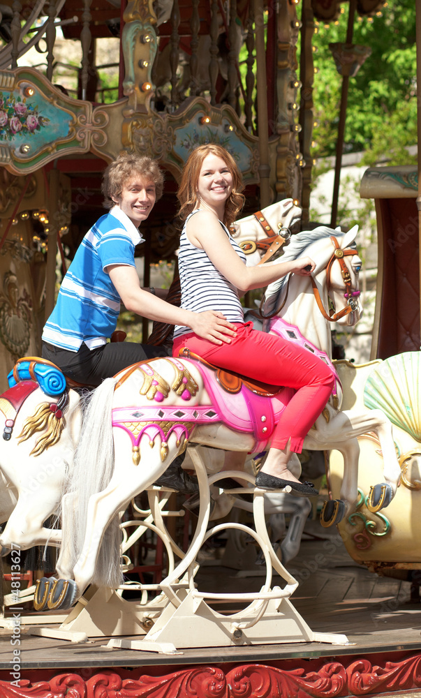 Obraz premium Happy young couple enjyong the ride on merry-go-round