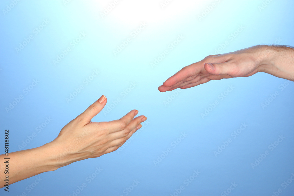 Women's hand goes to the man's hand on blue background