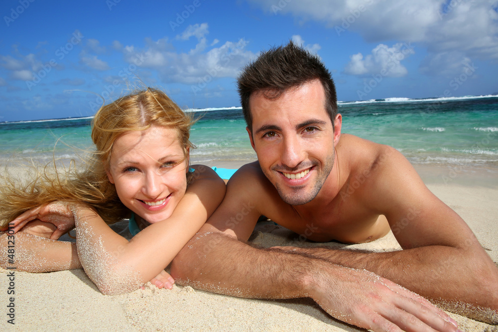 Cheerful young couple laying on a sandy beach Cheerful young couple laying on a sandy beach