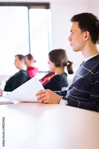 young, handsome male college student sitting in a classroom