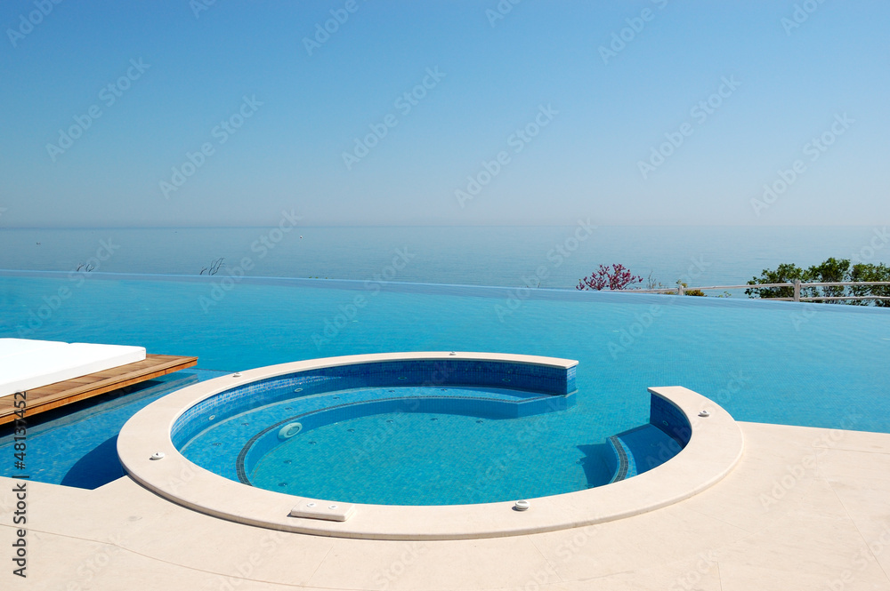 Infinity swimming pool with jacuzzi by beach at the modern luxur
