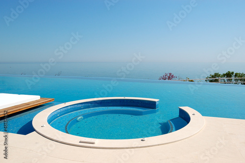 Infinity swimming pool with jacuzzi by beach at the modern luxur © slava296