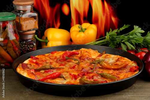 Tasty pepperoni pizza in pan with vegetables on flame