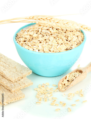 Blue bowl full of oat flakes with wooden scoop, spikelets and