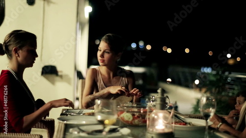 Female friends celebrating dinner on the terrace at night, stead photo