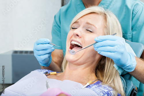 Dentist Treating A Female Patient At Clinic
