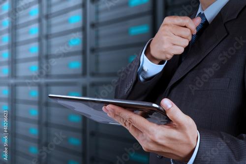 businessman hand using tablet computer and server room