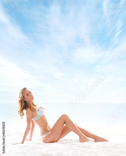 A young and sexy woman posing on a blue sky background