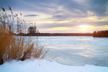 Winter landscape with sun and frozen river.