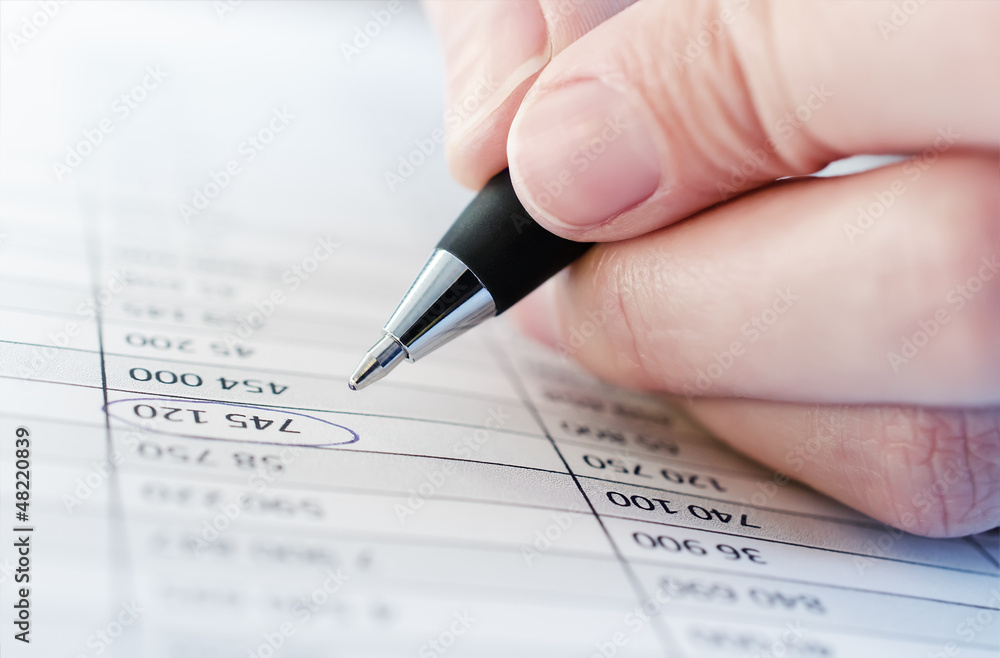 Hand is holding pen and writing in chart Hand is holding pen and writing in chart