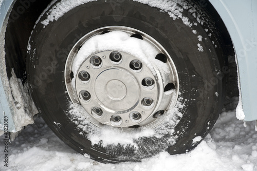 Detail of a coach’s tire on a road covered with snow.