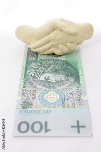 Splecione dłonie nad banknotem 100 zł 