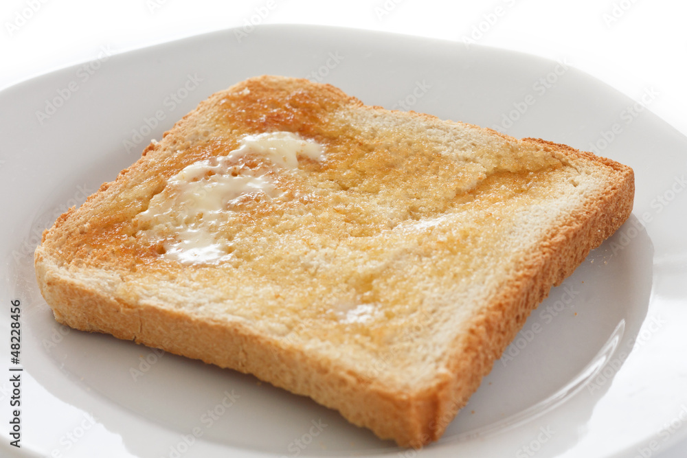 Slice of white buttered toast on a plate Slice of white buttered toast on a plate