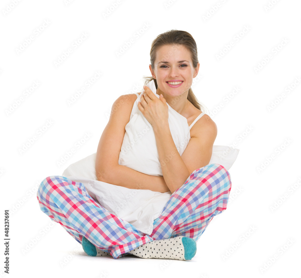 Smiling young woman in pajamas sitting with pillow Smiling young woman in pajamas sitting with pillow