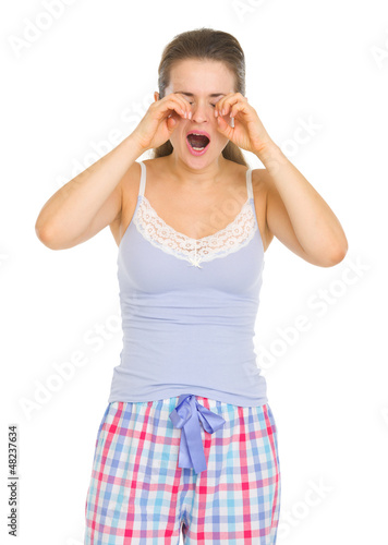 Young woman in pajamas rubbing eyes photo