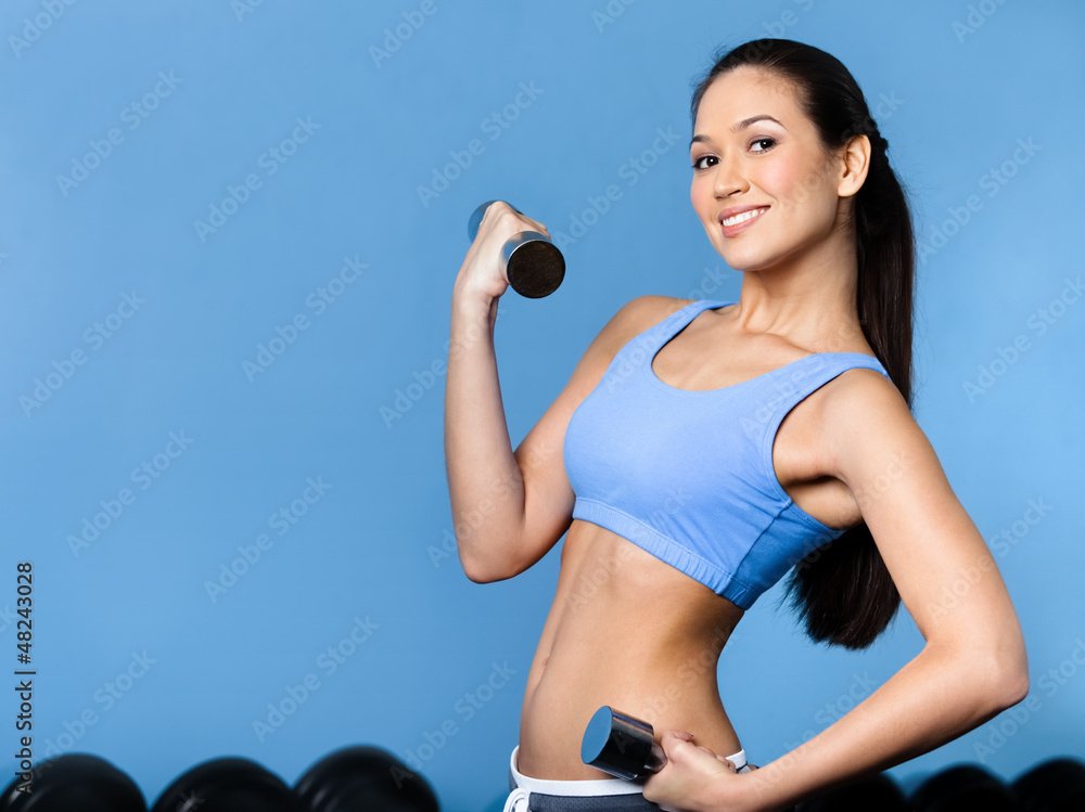 Sportswoman works out with dumbbells in gym Sportswoman works out with dumbbells in gym