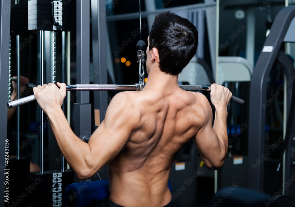 Athletic young man works out on training apparatus Athletic young man works out on training apparatus