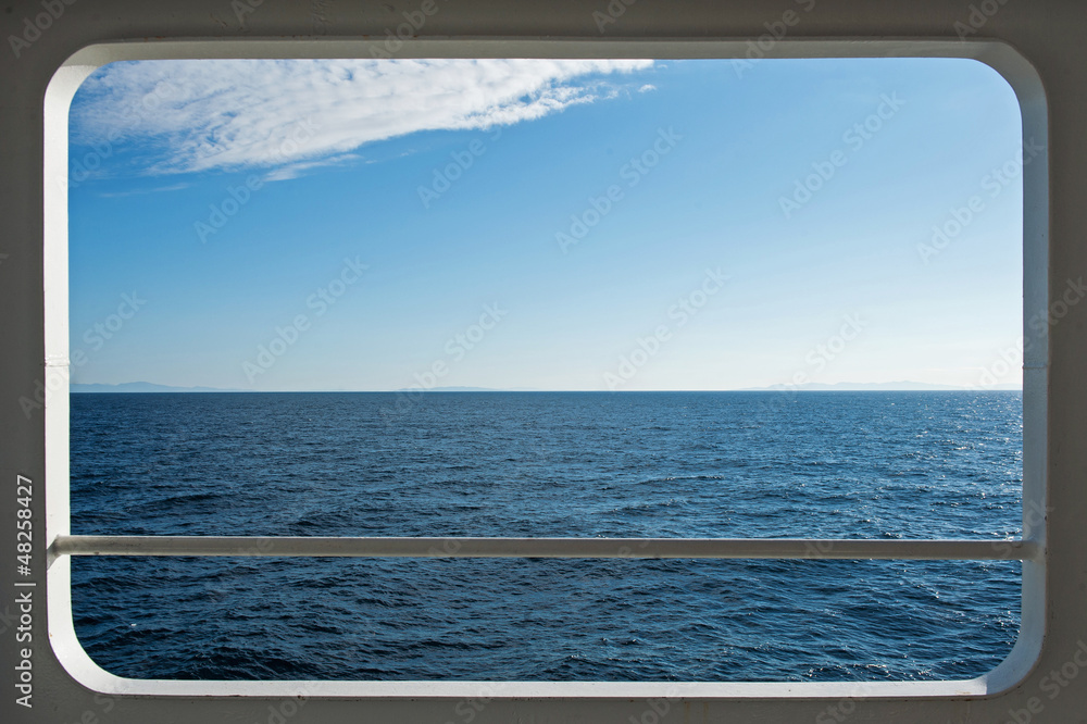 Fototapeta premium Ship window with a relaxing seascape and blue sky view.