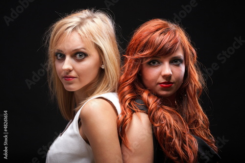 two happy young girlfriends black background