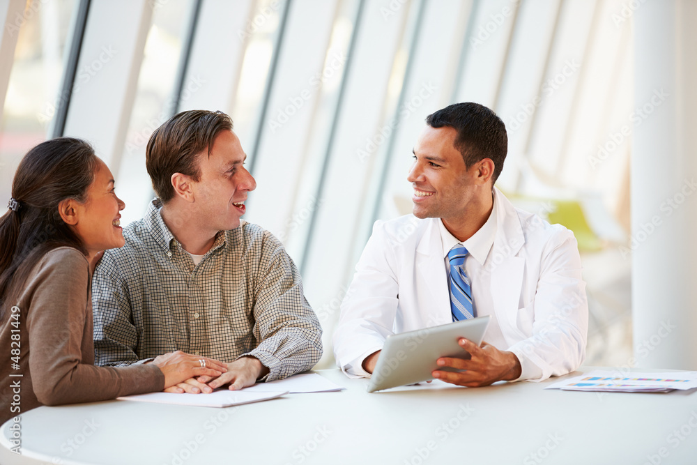 Doctor Using Tablet Computer Discussing Treatment With Patients Doctor Using Tablet Computer Discussing Treatment With Patients