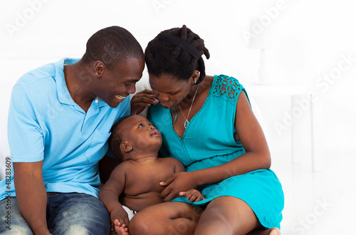 happy african american parents playing with baby boy in bedroom