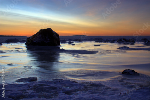 Sunrise in frozen beach in dark morning