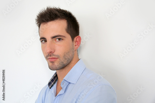 Serious young man standing on white background