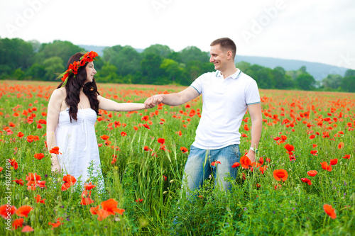 Happy couple walking in poppy field photo