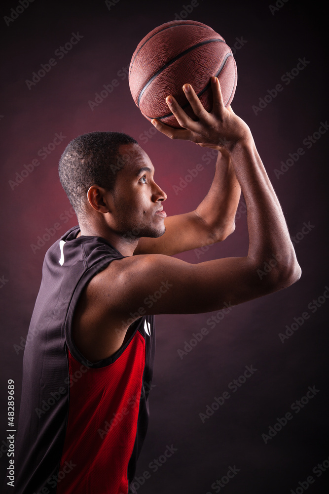 Portrait of a young male basketball player against black backgr Portrait of a young male basketball player against black backgr
