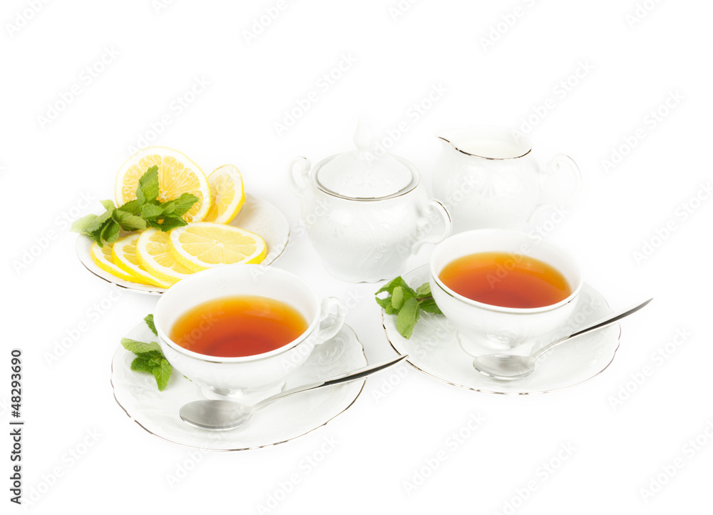 Two cups with tea, teapot, milk and lemon Two cups with tea, teapot, milk and lemon