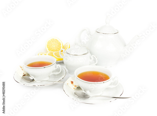 Two cups with tea, teapot, milk and lemon